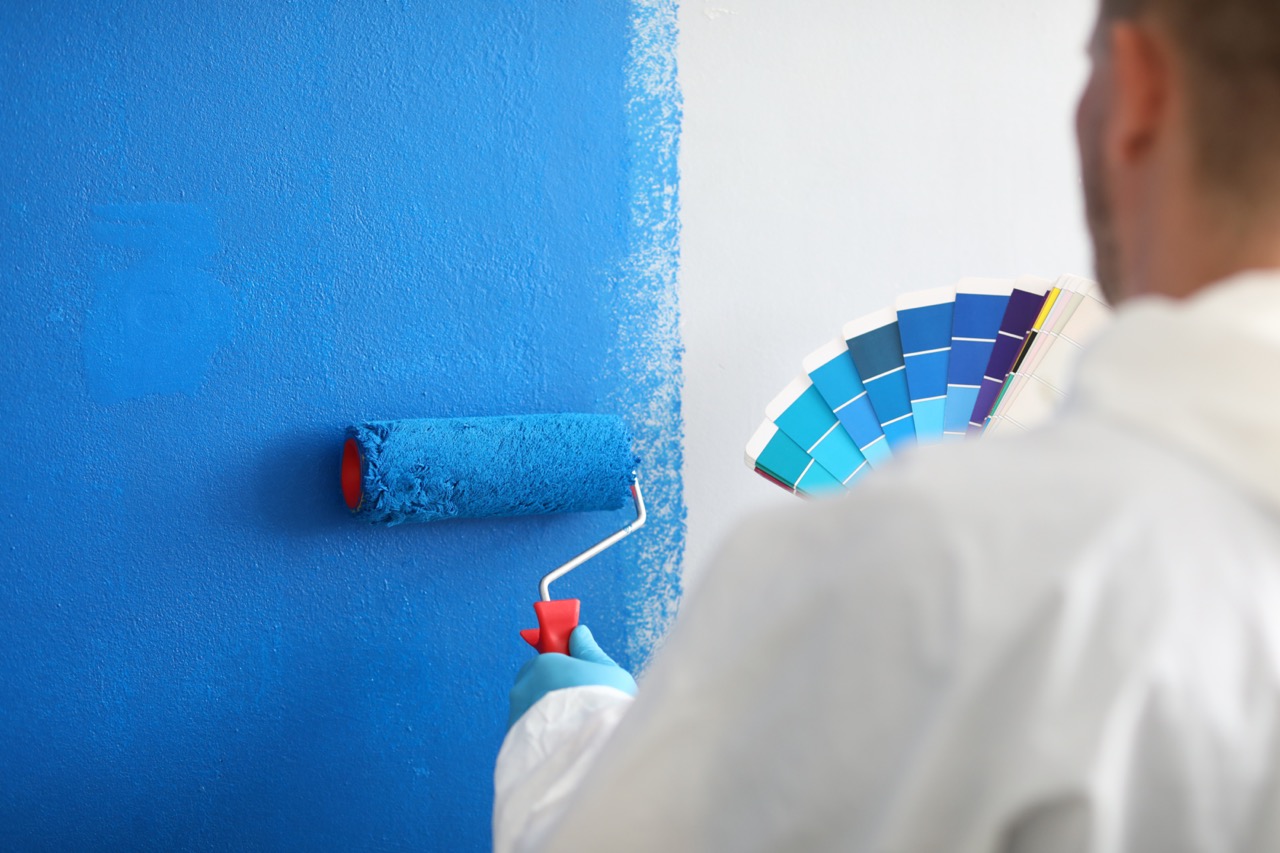 l-artigiano-tiene-il-rullo-e-una-tavolozza-di-colori-e-dipinge-il-muro-bianco-blu-servizi-di-pittura-murale-e-concept-di-pittura – dimensioni grandi